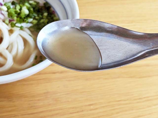 カルディ「麺にかけるだけ 鮭レモンつゆ」のつゆをレンゲですくっている様子