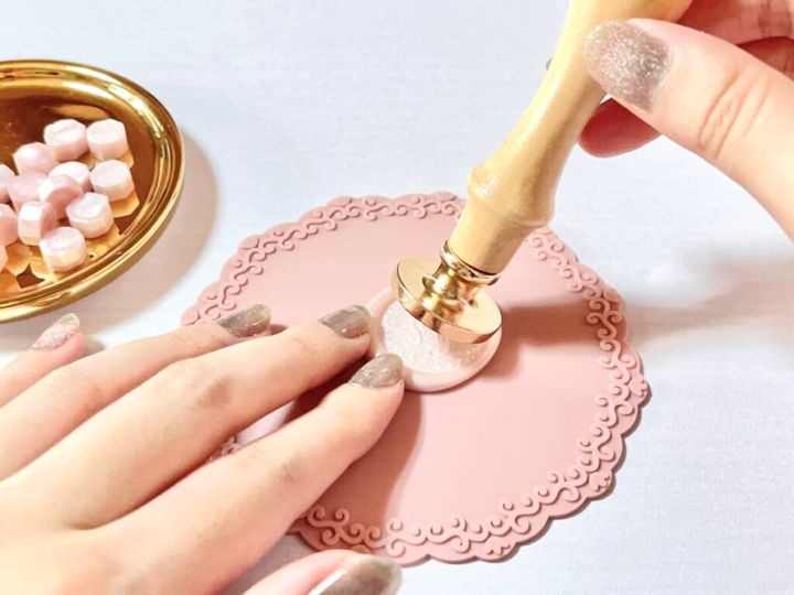 「シーリングスタンプ用 シリコーンマット」で固めた「シーリングワックス 粒タイプ」リッチピンクカラーを「シーリングスタンプ用 ハンドル」と「シーリングスタンプ用 スタンプヘッド」から外していく様子