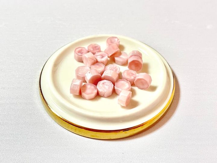 ダイソー「シーリングワックス 粒タイプ」のリッチピンクカラーをトレイに乗せて紹介する画像