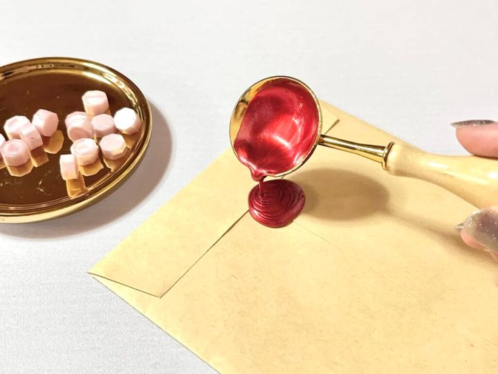 溶かした「シーリングワックス 粒タイプ」ボルドーレッドカラーを封筒にたらして封をする様子