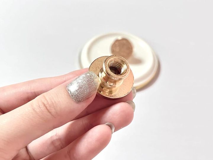 ダイソー「シーリングスタンプ用 スタンプヘッド」を手に持ち、ナット部分をアップで紹介する画像