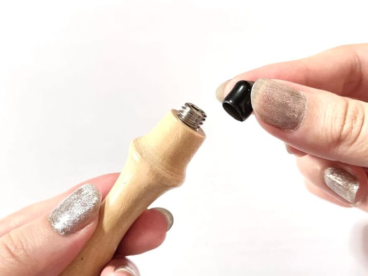 ダイソー「シーリングスタンプ用 ハンドル」を手に持ち、黒いキャップを取り外す様子