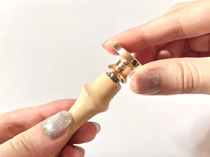 ダイソー「シーリングスタンプ用 ハンドル」を手に持ち、「シーリングスタンプ用 スタンプヘッド」を取りつける様子