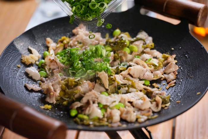 ネギを加えて炒め合わせている様子