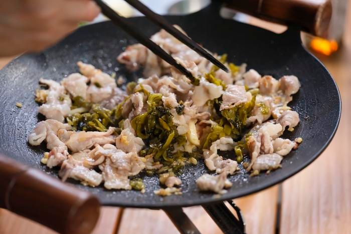 高菜を加えて炒め合わせている様子