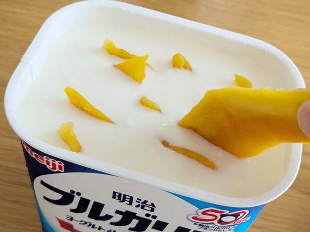 ブルガリア ヨーグルトに牛乳・ハチミツ・ブルガリアヨーグルトを入れスて混ぜ、ドライマンゴーを入れている様子