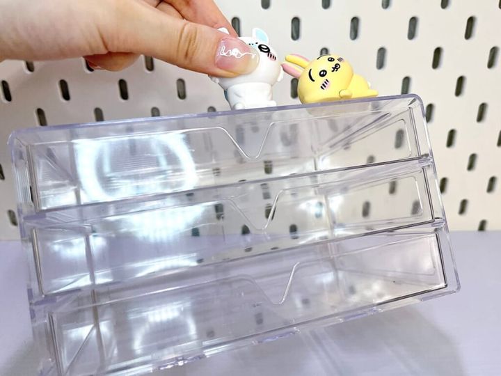 クリアケースに両面粘着ゲルテープ「KAERU GRIP（カエルグリップ）」に貼りつける、漫画『ちいかわ』の登場キャラクター「モモンガ」「うさぎ」を固定し、手で持って強度を確かめている様子