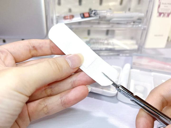 ドウジシャ「救急！！キズテープ」を手に持ち、ハサミで片側に切り込みを入れている様子