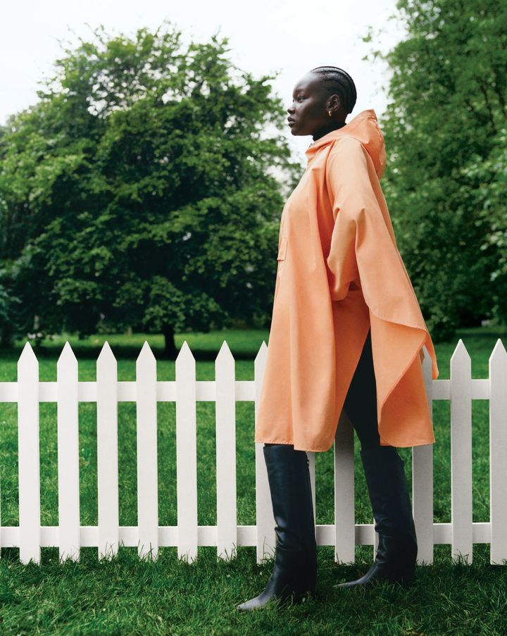 オレンジのポンチョ ¥317,900/LOVEFROM, MONCLER（モンクレール ジャパン）※10月10日(木)より発売予定 イヤリング／KENDRA SCOTT （www.kendrascott.com）ブーツ ¥239,800/JIMMY CHOO（ジミー チュウ）