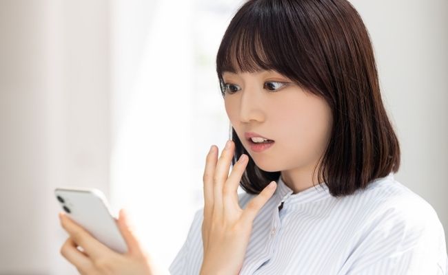 スマホを見て驚く女性