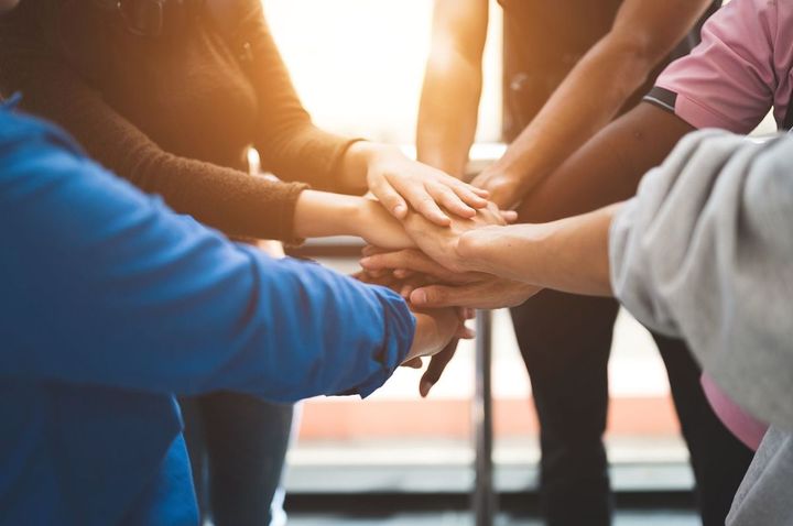 円陣を組んで手を重ねる人々