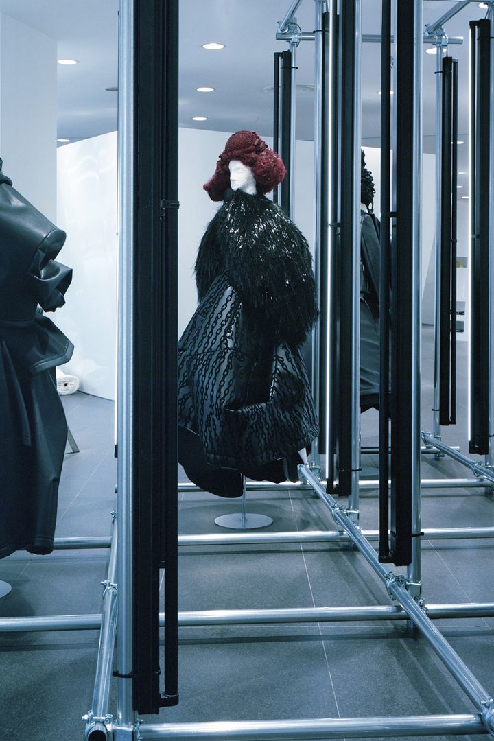 最先端のモードとともに童心に返る場所<br /> 白を基調とし、曲線が印象的なコム デ ギャルソン青山店。商品が見えそうで見えない構造は、まるで童心に返り服とかくれんぼをしているかのように、店内を歩くたびに新鮮な驚きと発見をもたらしてくれる。春夏、秋冬シーズンごとに変わるディスプレイやコンセプトも、すべて川久保自身によるもの。2024 -25秋冬コレクションでは、ショップの入り口正面に同シーズンのルックが4体並び、訪れる人の感性を挑発する。