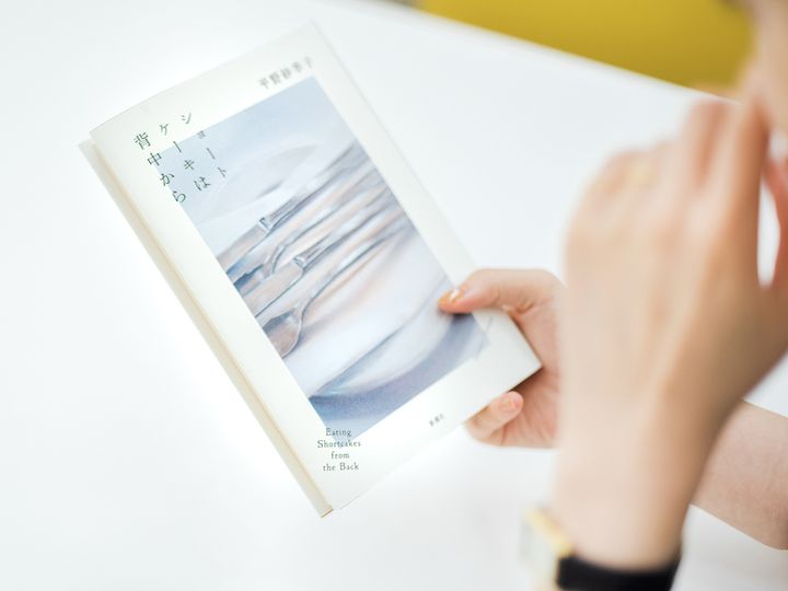 書籍『ショートケーキは背中から』を持つ平野紗季子