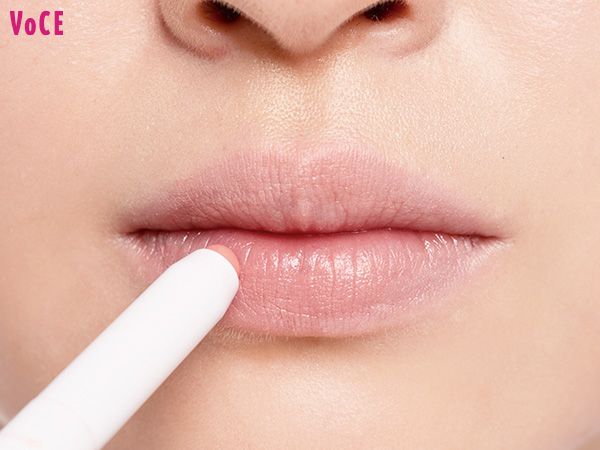 肌になじむ淡いピンクのリップベースで、唇の色とカタチを整える。