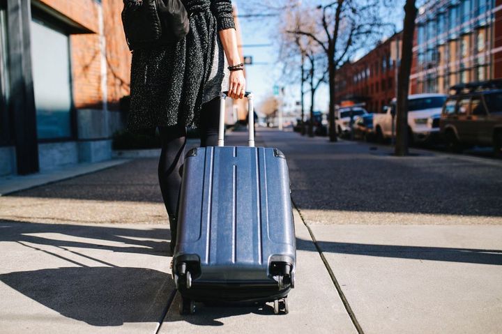 カリフォルニア州サンフランシスコの路上で、スーツケースを持ち、宿泊施設や旅行所に行く若い女性