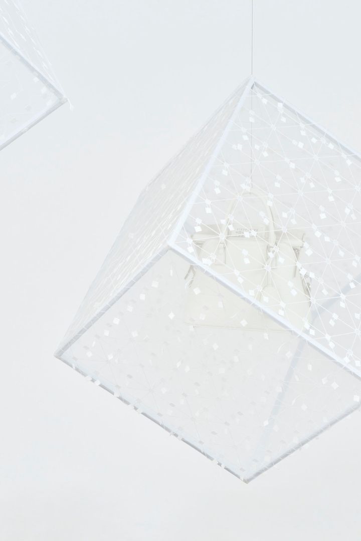 四角い刺繍片がテキスタイルの一部となり、揺れ動くNUNOの刺繍布「スイング四角」の制作工程を、3つのキューブで表現した「ヌノ｜ウィープラス」の作品「回転するキューブ」