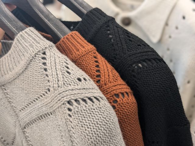 ラックにかけられた透かし編みニットクルーネックセーター