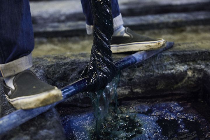 枷糸を掛けてある木の棒を足で抑え込んで、絞り上げる様子