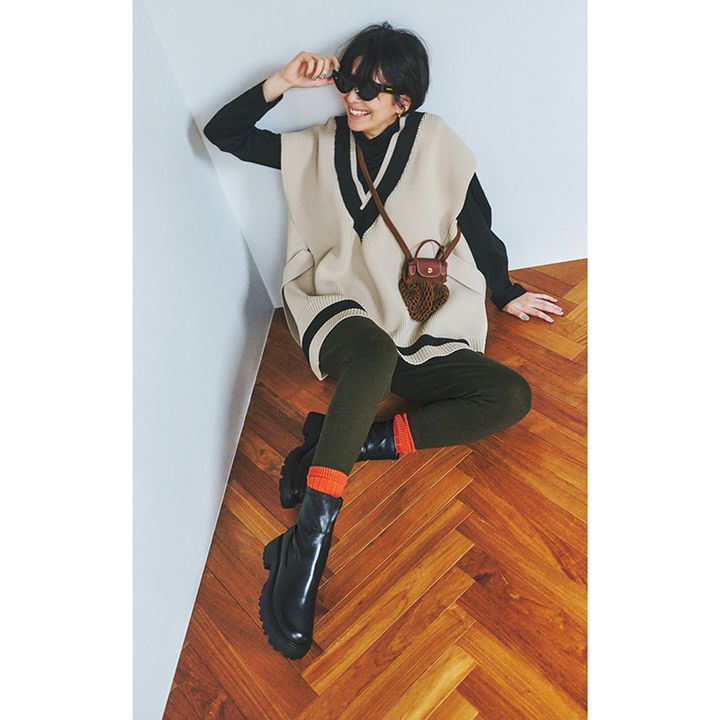 ベージュのラインニットベストにレギンス、足元レイヤードコーデ