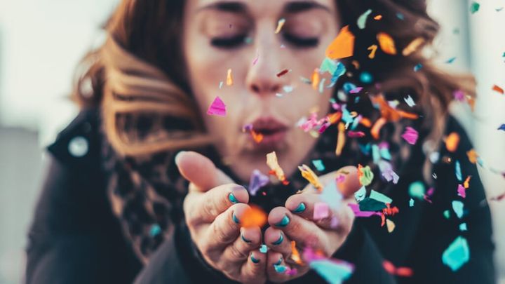 woman blowing paper strips in selective focus photography