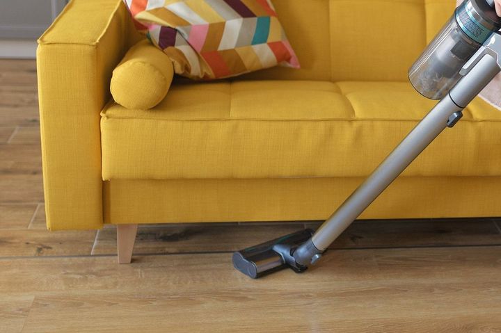 スティック型掃除機でソファの下を掃除する