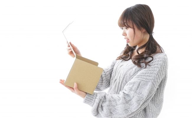 段ボールを開けて驚く女性