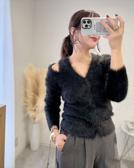 黒のカットアウトカーディガンを着ている