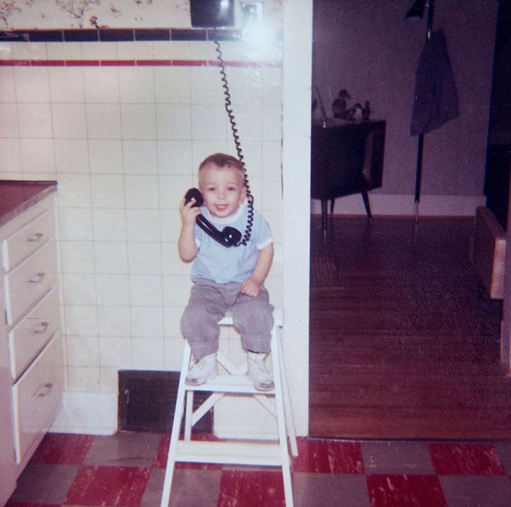 Young boy talks on the phone in the family 1960s era kitchen.