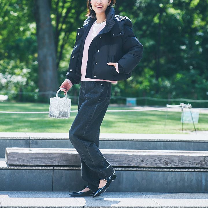 ゆるっとしたカーブデニムとピンクニットに黒の中綿アウターを羽織った着こなし