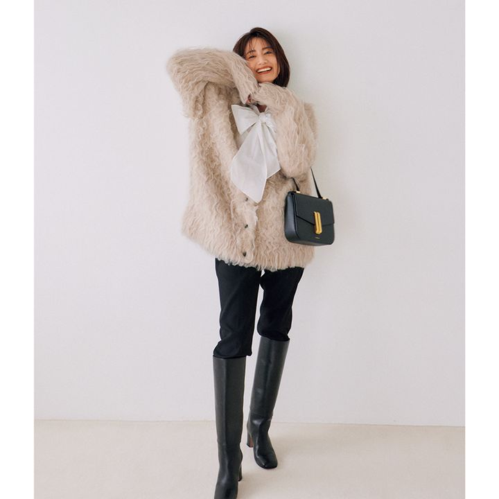 もけもけベージュカーデにリボンブラウス、黒ボトムにロングブーツのコーデ