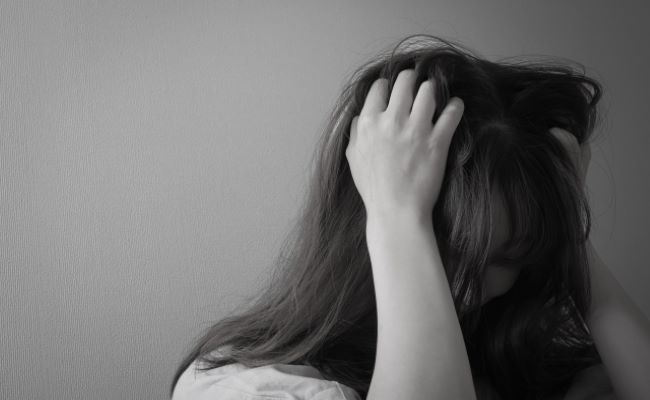 頭を抱えるつらそうな女性