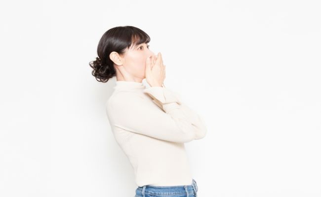 白い背景の前に立って驚いている女性