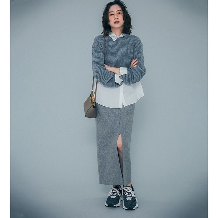 グレーのニットとスカートの間に白シャツを挟んだワントーンコーデ