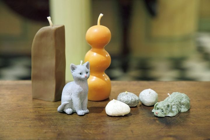 【Cerería Subirá セレリア・スビラ】犬のキャンドル€7、小石のキャンドル各€1、猫のキャンドル€10。 奥にある幾何学モチーフのキャンドル€21（右）、€18（左）。