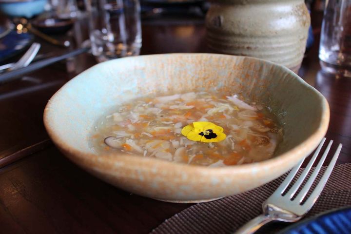 前菜のカニ爪のスープ。上に浮かぶお花がかわいらしい