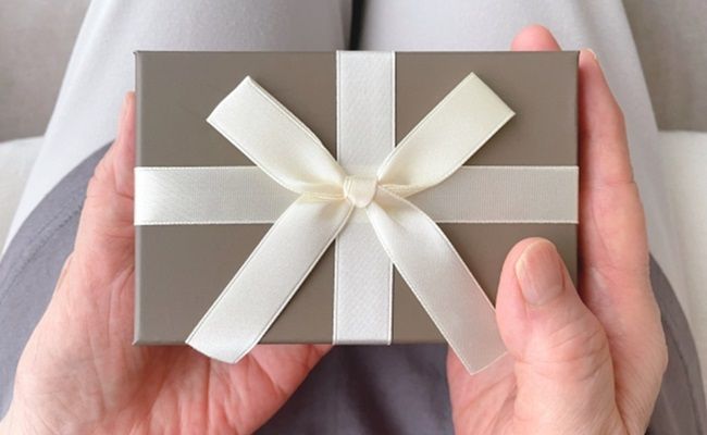 膝の上でプレゼントを持つ女性の手元