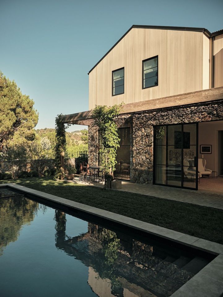 テラスに置かれたテーブルとチェアは、パリの蚤の市で見つけた、1950 年 代のロジェ・キャプロンの作。ハンギングバスケット風の照明はサントロペで購 入。壁には天然石を貼り、脱色したヒマラヤスギのサイディングを使用。敷石に は再生された小石を利用している。