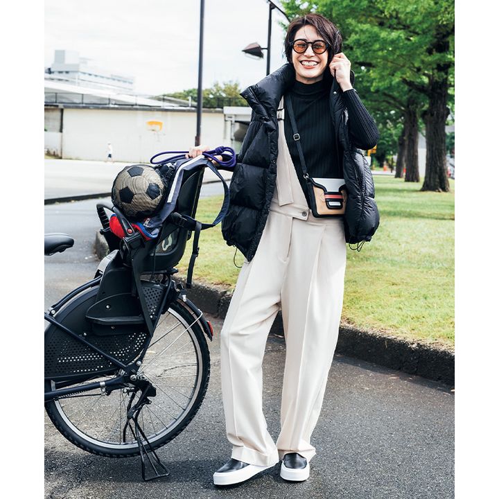 黒タートルにクリーム色のワンショルダーのサロペットと黒ダウンベストをあわせてカラフルなショルダーバッグを斜めがけしたママコーデ