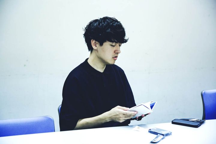 「THE TOKYO TOILET」のガイドブックを読む奥山大史。