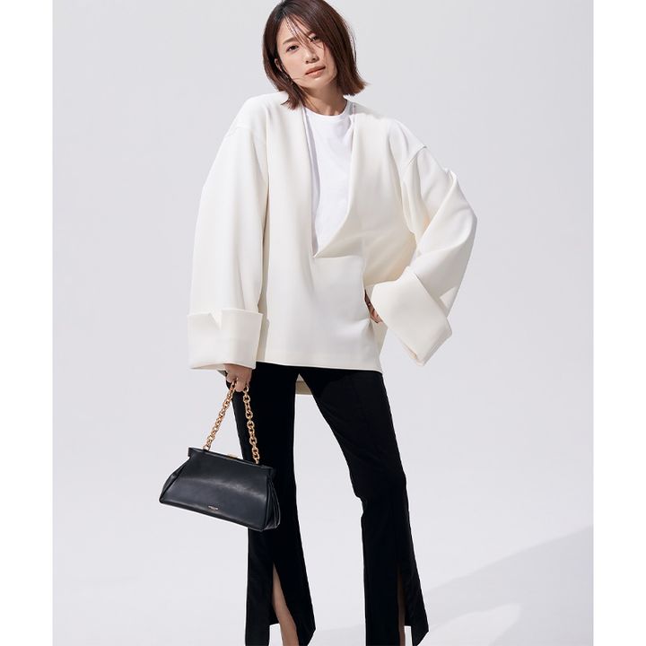 白の個性派シルエットのトップスにスリット入りスティックパンツ