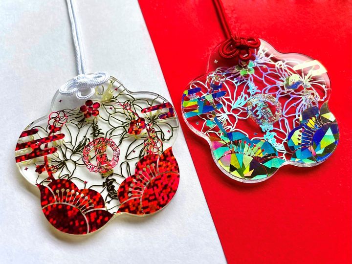 光に当てると、七色に美しく輝く「うめおまもり」。紅梅（左）、白梅（右）の2色からセレクトできる。