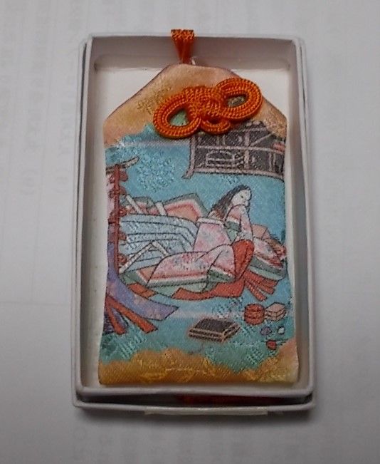 表は十二単をまとった女性、裏は装束姿の男性が描かれた「開運招福お守り」。なんと西陣織で作られているのだとか。