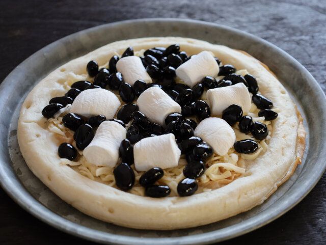 冷凍ピザクラストの上にピザ用チーズを広げて、黒豆とマシュマロを乗せる