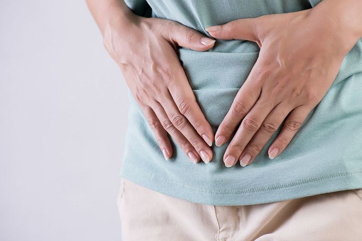 下腹部を手で押さえる女性