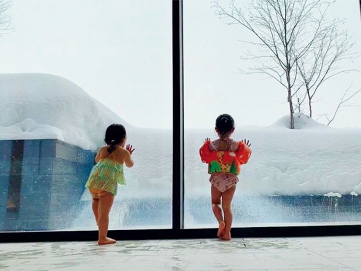 ホテルのプールから雪景色を眺める子どもたち