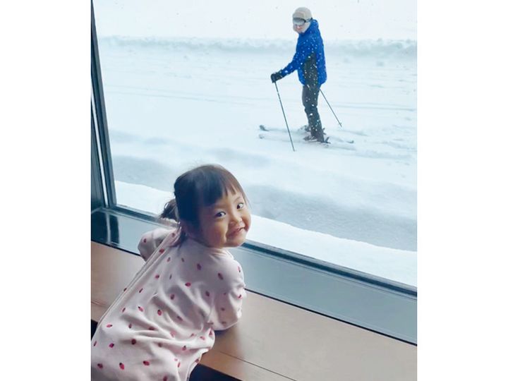 ホテルの窓からスキー場を眺める子ども