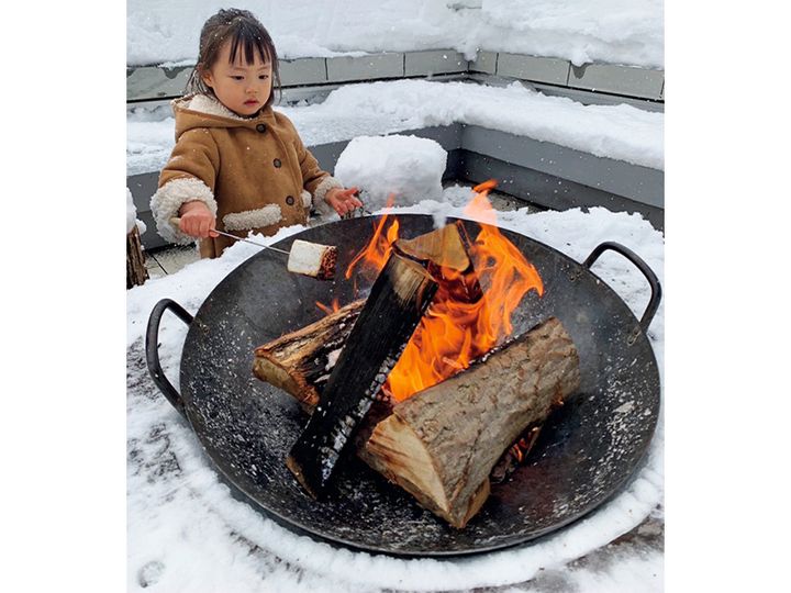 雪景色の中マシュマロを暖炉で炙る子ども