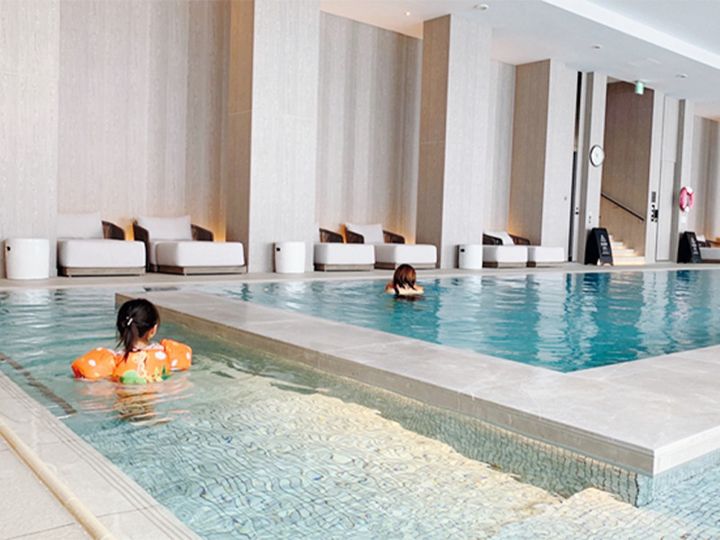 ホテルのプールで泳ぐ子どもと女性