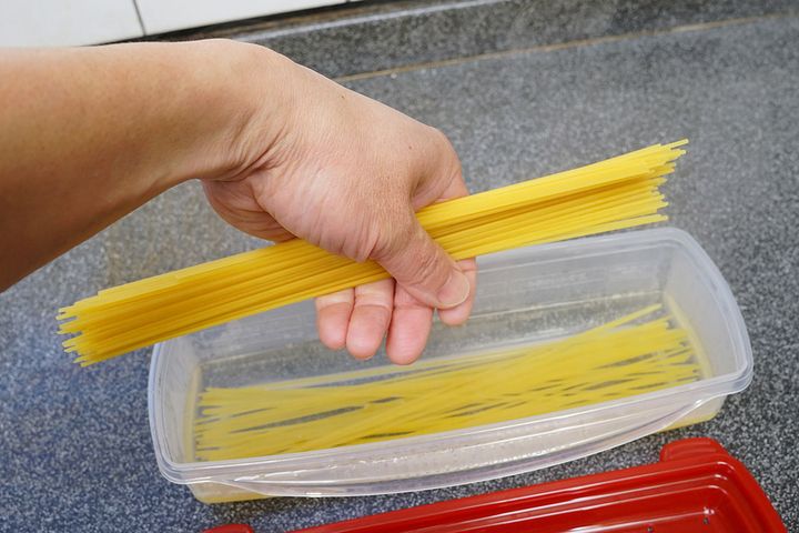 規定量の熱湯を入れた「絶品レンジでパスタ」本体に、パスタ同士がくっつかないようにパラパラと1本ずつパスタを投入します。