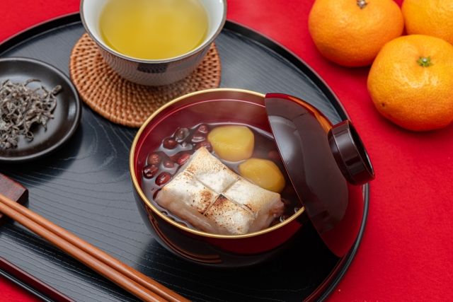 お盆におしることお茶が乗せられている 横にみかん